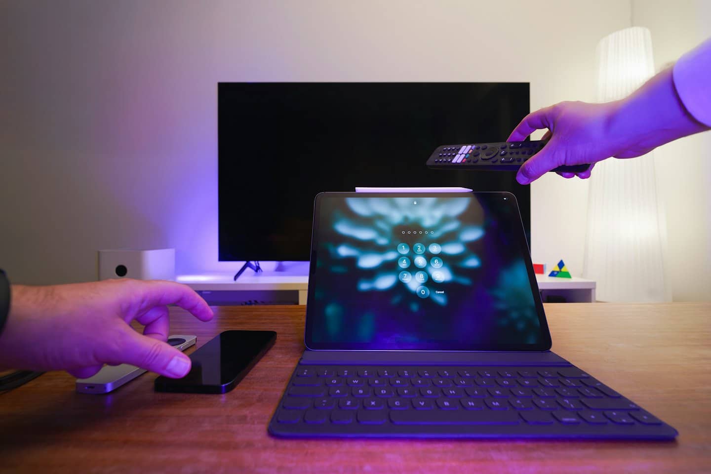 Ruky ovládajúce technológiu inteligentnej domácnosti na stole.